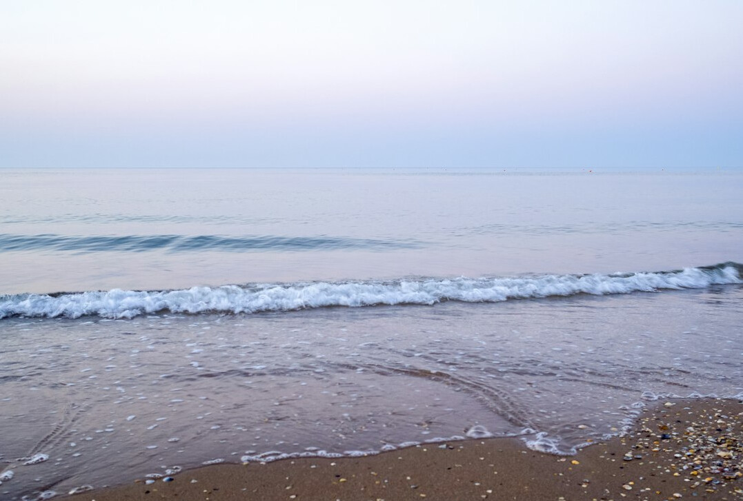 Calm sea coastline with waves at sunset
